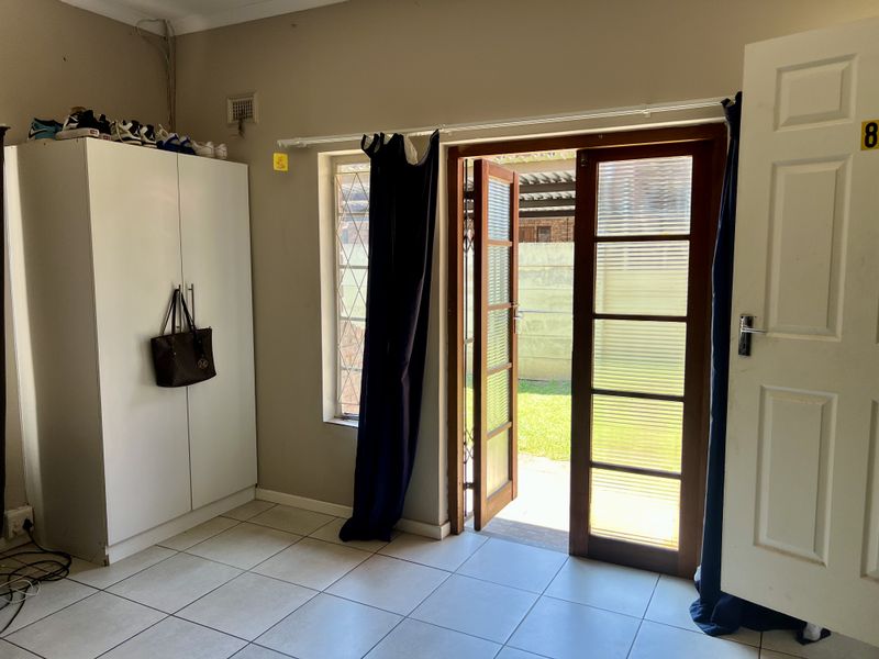 Bedroom featuring tiled flooring, a built-in wardrobe, and direct access to the garden through timber-framed glass doors.