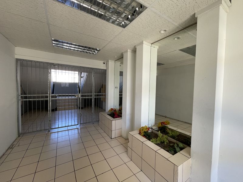 An entrance foyer featuring tiled flooring, built-in planters, mirrored wall accents, and a secure metal gate leading to the stairwell.