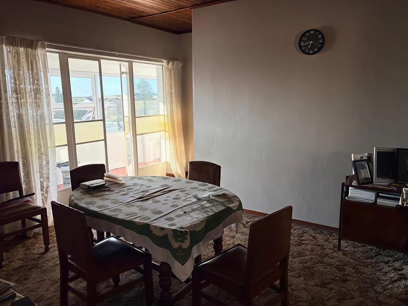 A dining area featuring timber ceilings, carpeted flooring, and a large sliding glass door providing natural light and access to the exterior.