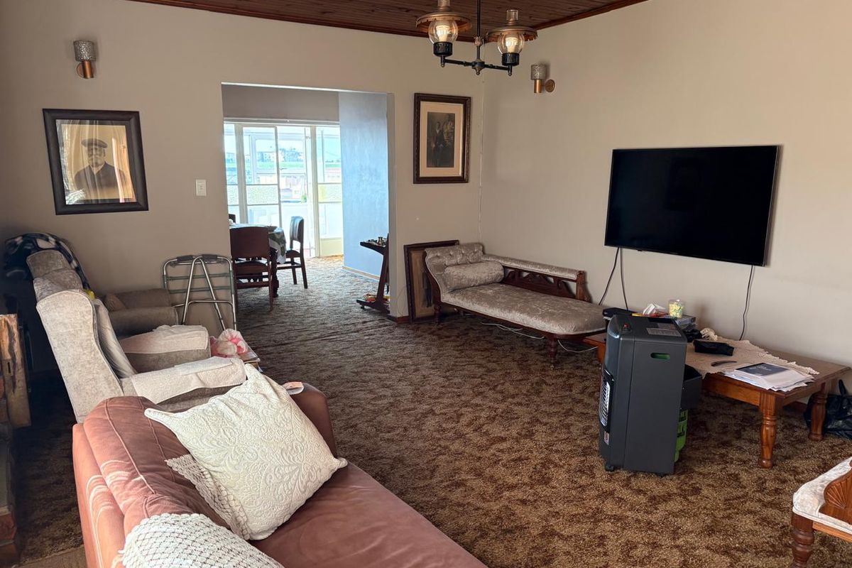 Spacious living room featuring a timber ceiling and wall sconces, leading through to an adjacent dining area.