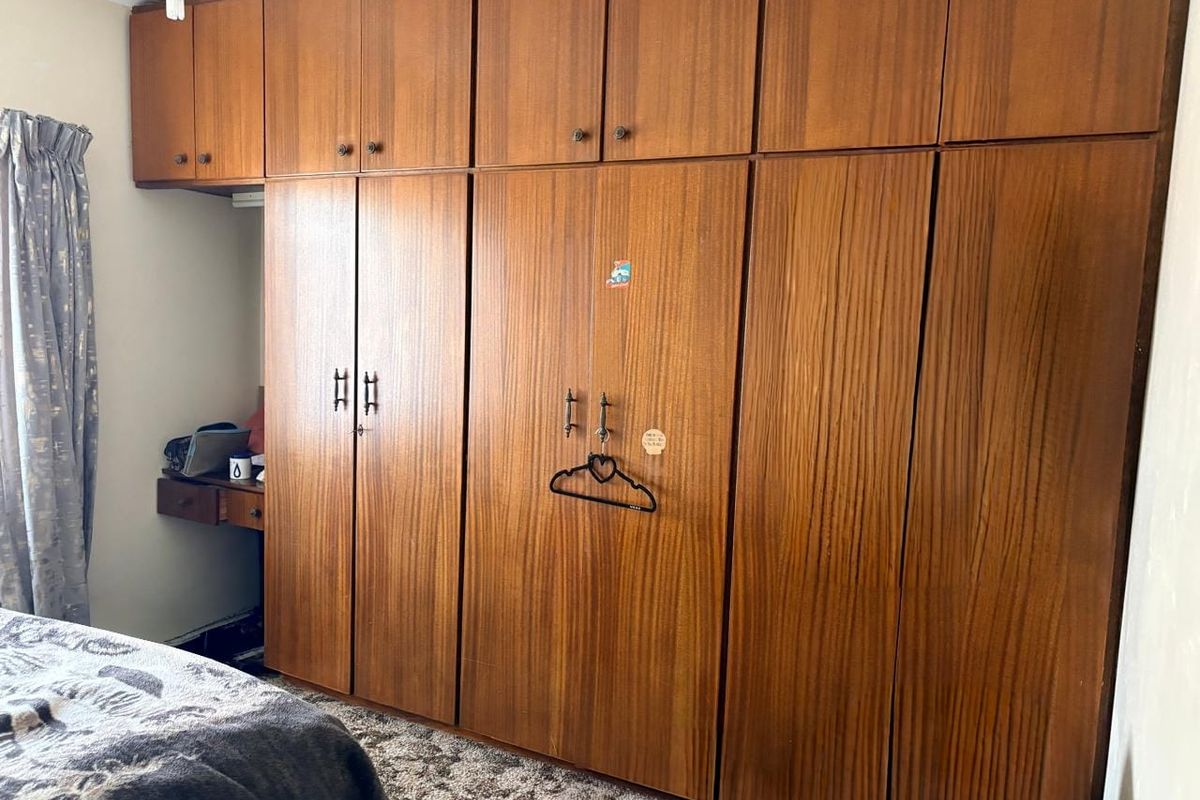 Bedroom featuring extensive floor-to-ceiling wooden built-in cupboards and a small integrated desk area.