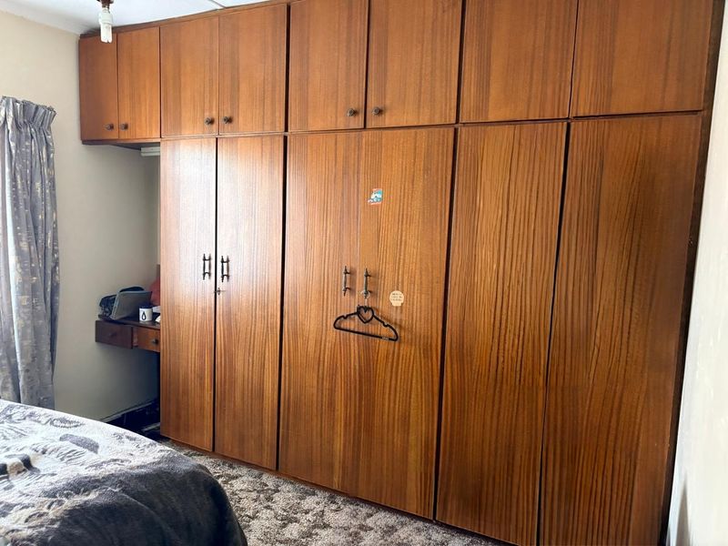 Bedroom featuring extensive floor-to-ceiling wooden built-in cupboards and a small integrated desk area.