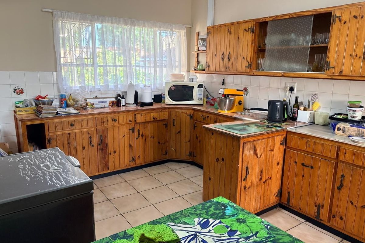 A functional kitchen featuring traditional pine cabinetry, tiled backsplash, and tiled flooring, offering a classic layout with ample storage space.