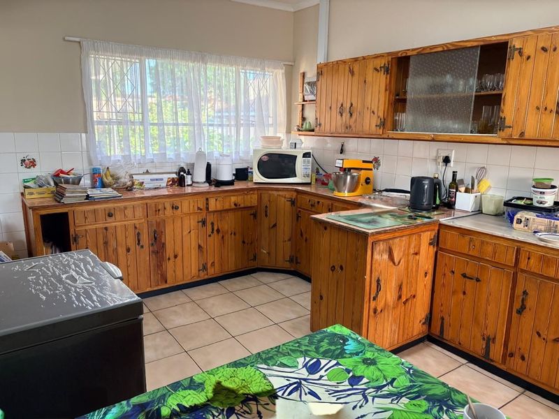 A functional kitchen featuring traditional pine cabinetry, tiled backsplash, and tiled flooring, offering a classic layout with ample storage space.