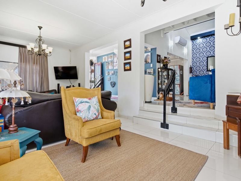 Spacious living area featuring tiled flooring, a split-level layout with a staircase, and wall-mounted air conditioning, offering a versatile open-plan living space.