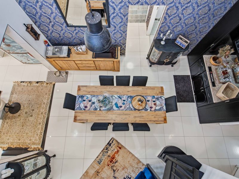 An overhead view of an open-plan dining and living area featuring tiled flooring, decorative wallpaper, and built-in cabinetry.