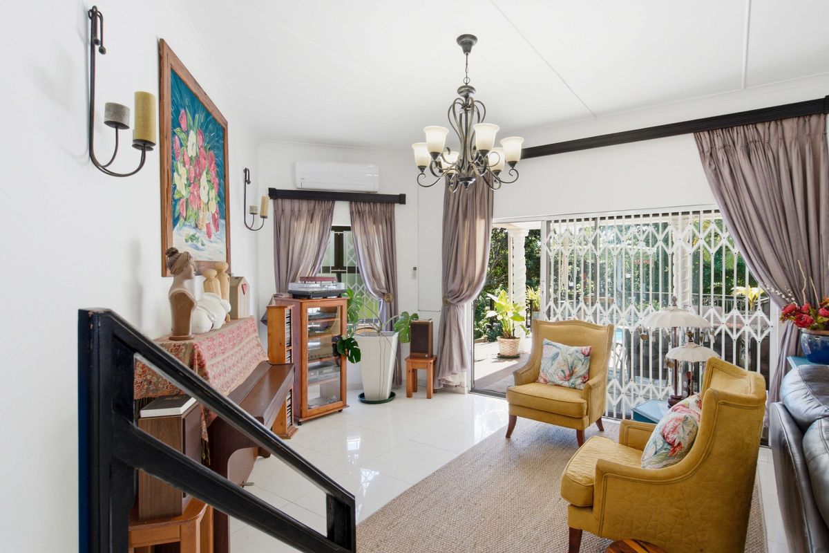 A bright living room featuring tiled flooring, a chandelier, and a sliding glass door providing access to the outdoor patio area.