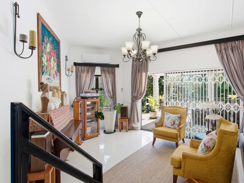 A bright living room featuring tiled flooring, a chandelier, and a sliding glass door providing access to the outdoor patio area.