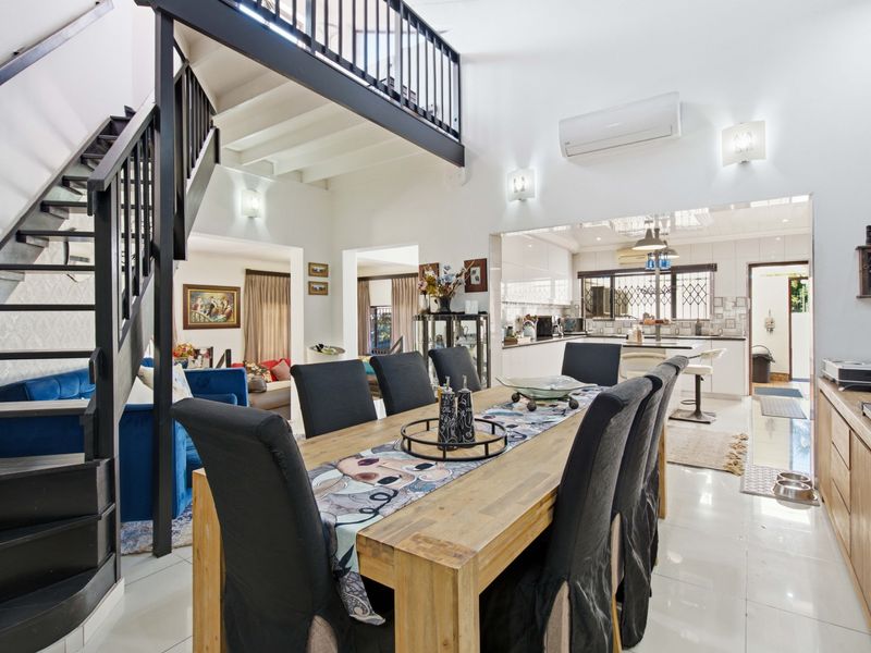 Spacious open-plan living and dining area featuring a modern staircase, mezzanine level, and a well-appointed kitchen with integrated cabinetry.