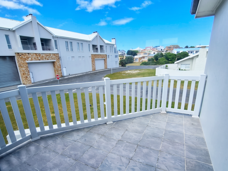 A clean, tiled balcony featuring a white balustrade with views over the surrounding residential complex and street.
