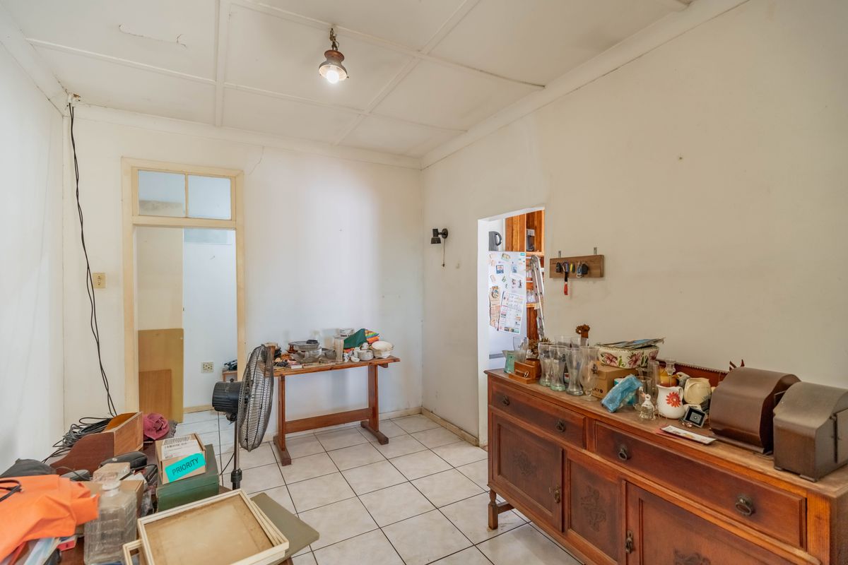 A living area featuring tiled flooring and a tiled ceiling, requiring cosmetic updates to address visible wall and ceiling cracks.