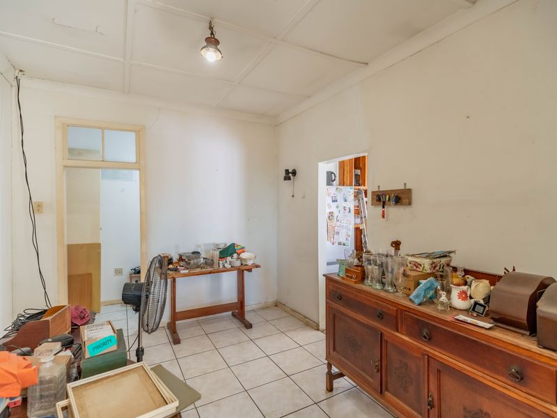 A living area featuring tiled flooring and a tiled ceiling, requiring cosmetic updates to address visible wall and ceiling cracks.