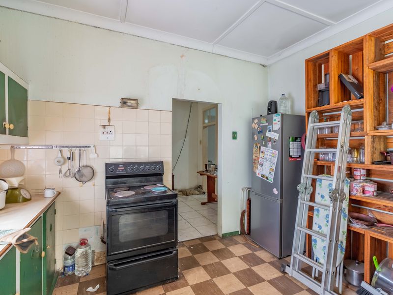 A dated kitchen featuring original cabinetry, tiled splashbacks, and a freestanding stove, offering significant potential for a modern renovation and layout update.