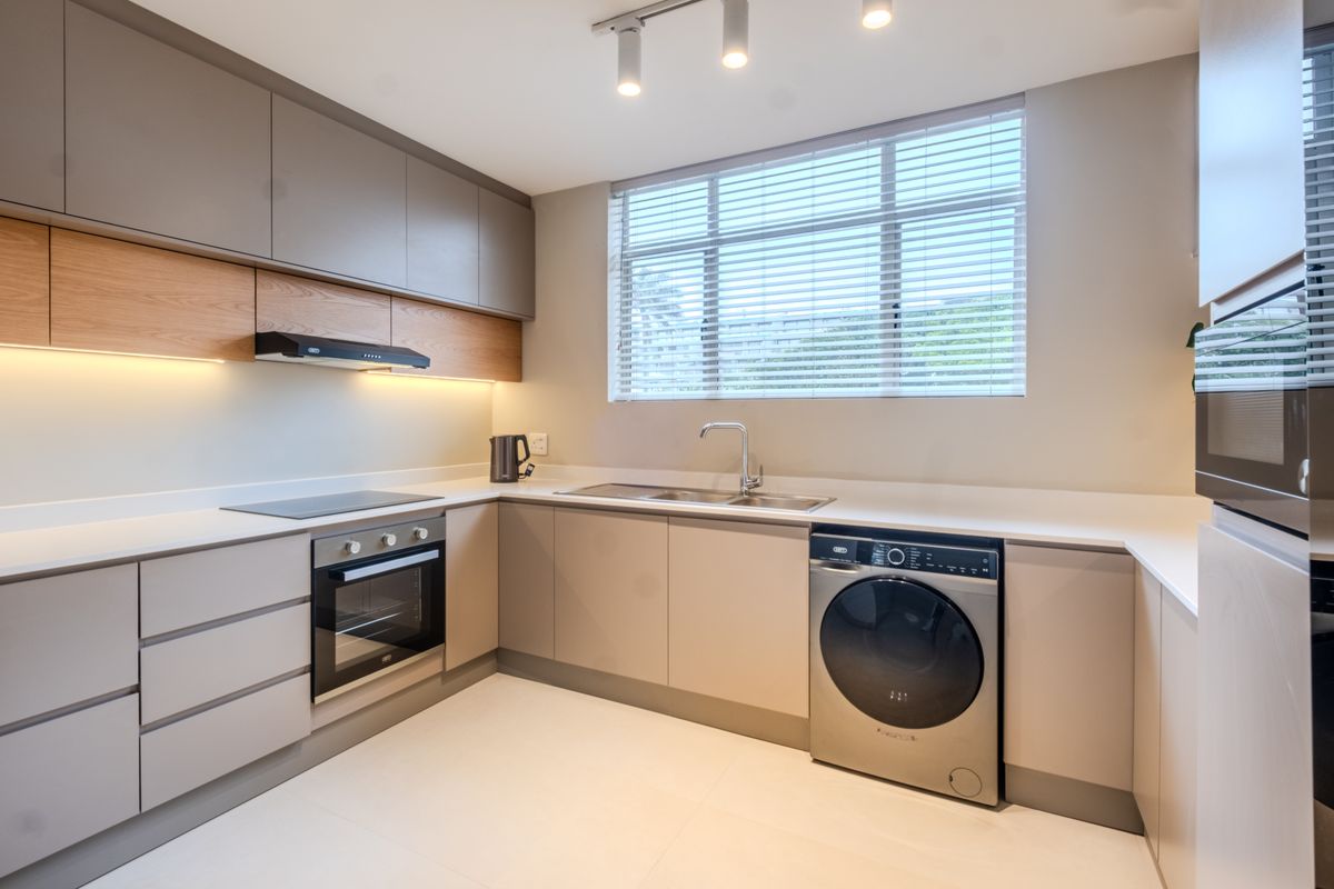 Modern kitchen featuring sleek handleless cabinetry, quartz countertops, integrated appliances, and high-quality finishes with ample natural light.