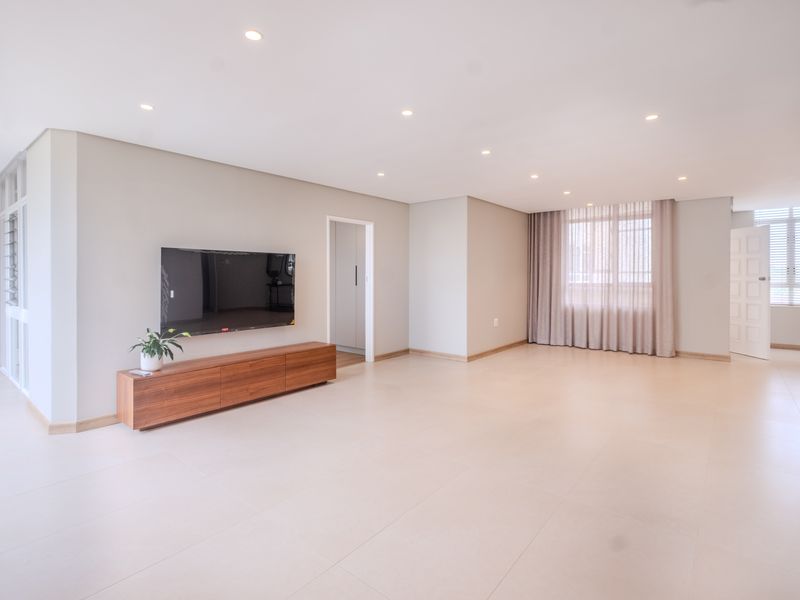 Spacious and bright living area featuring neutral tiled flooring, recessed downlighting, and clean finishes, offering a versatile open-plan layout.