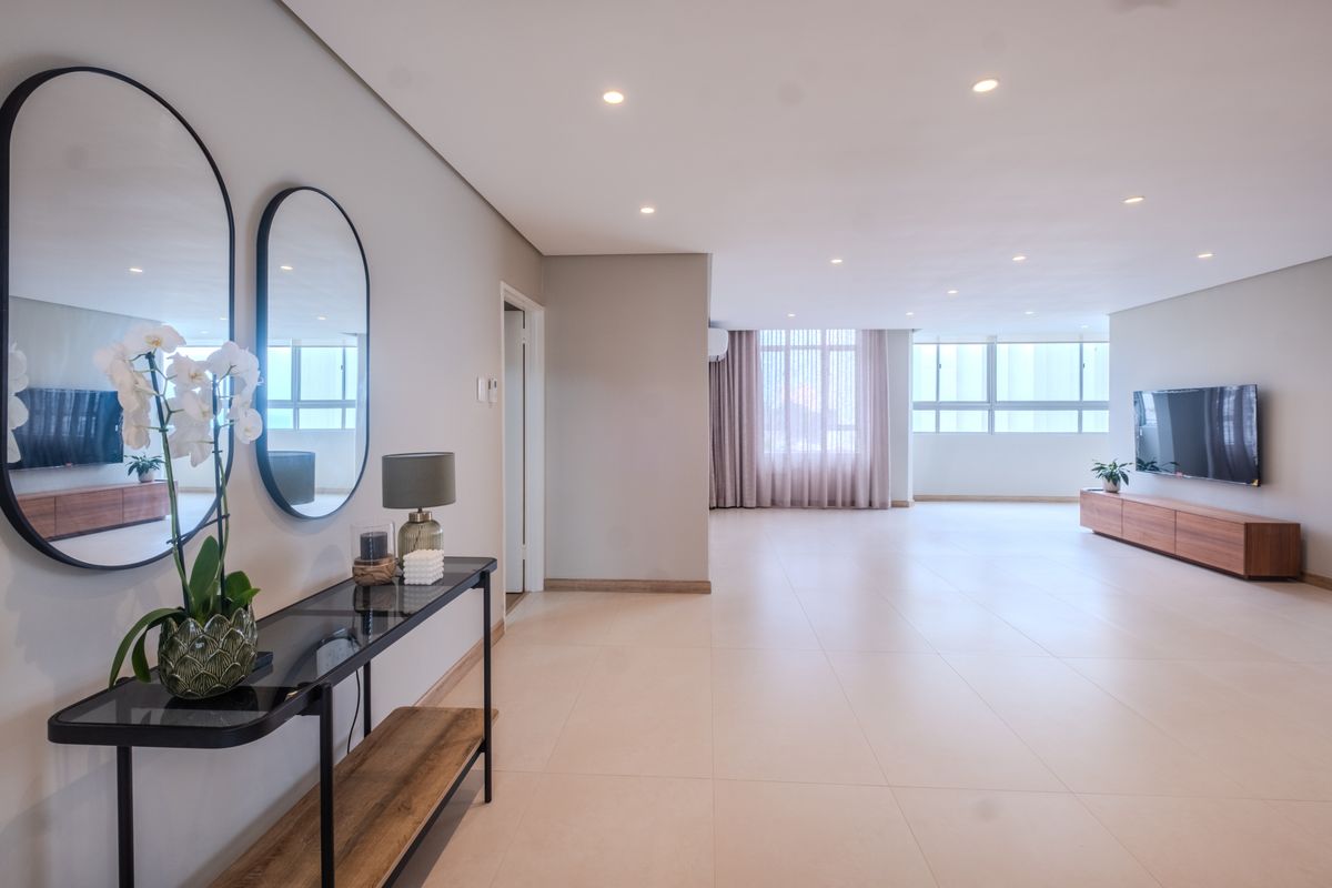 Spacious and bright living area featuring neutral tiled flooring, recessed downlighting, and large windows that provide ample natural light.