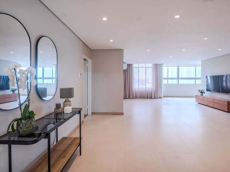 Spacious and bright living area featuring neutral tiled flooring, recessed downlighting, and large windows that provide ample natural light.