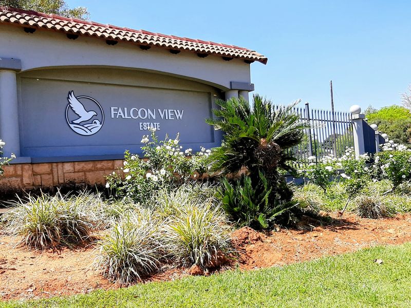 The entrance to Falcon View Estate featuring a well-maintained stone-clad signage wall, perimeter fencing, and established garden landscaping.