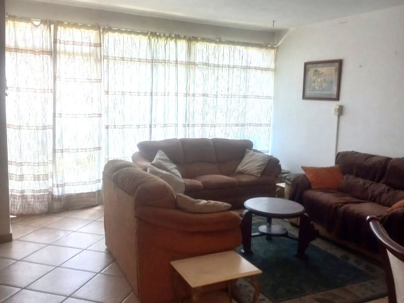 A spacious living room featuring large floor-to-ceiling windows that provide ample natural light and durable tiled flooring throughout.