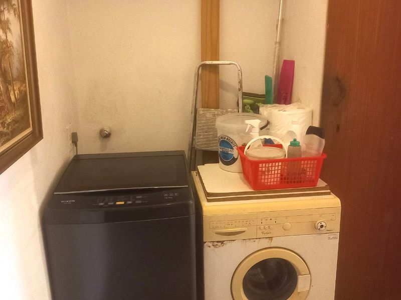 A functional laundry area featuring tiled flooring and built-in cabinetry, providing space for laundry appliances and utility storage.