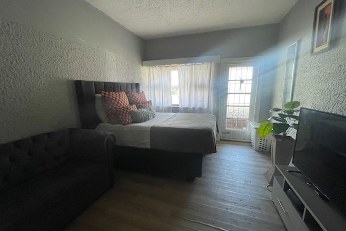 A bedroom featuring textured walls, laminate flooring, and a glass panel door providing natural light and outdoor access.