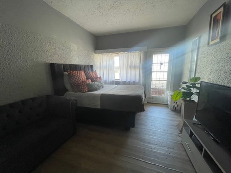 A bedroom featuring textured walls, laminate flooring, and a glass panel door providing natural light and outdoor access.