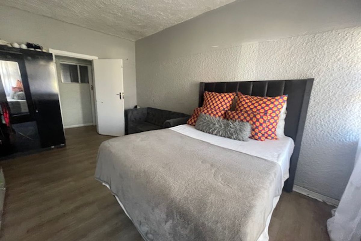 A bedroom featuring laminate flooring and textured wall finishes, offering a functional space ready for cosmetic updates.
