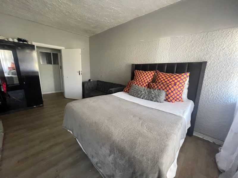 A bedroom featuring laminate flooring and textured wall finishes, offering a functional space ready for cosmetic updates.
