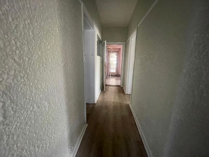 A functional hallway featuring laminate flooring and textured walls, providing access to various rooms within the flat.
