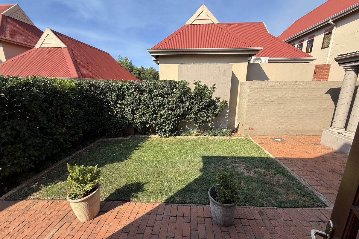 A private rear garden featuring a well-maintained lawn, brick-paved patio area, and established perimeter hedging, providing a pleasant outdoor space.
