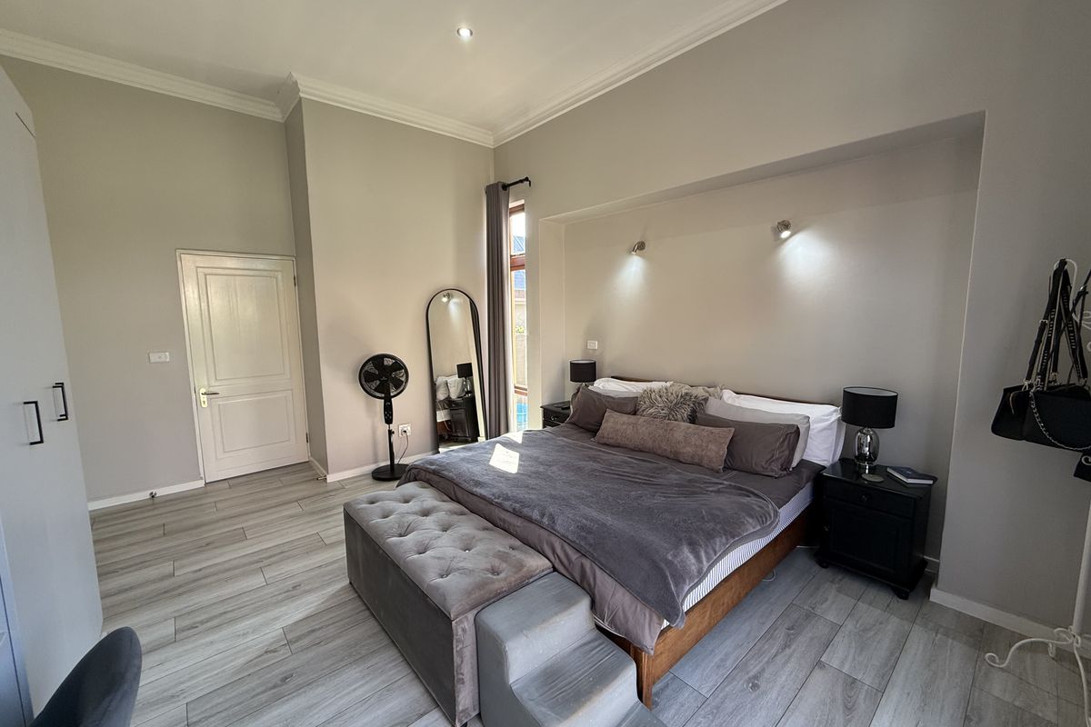 Spacious bedroom featuring modern laminate flooring, recessed ceiling lighting, and built-in wall sconces, creating a comfortable and well-lit living space.