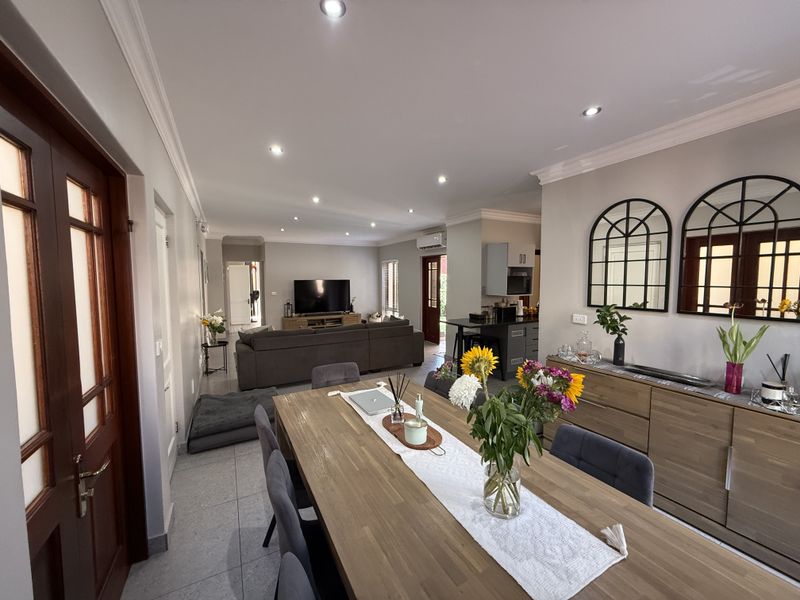 Spacious open-plan living and dining area featuring tiled floors, recessed lighting, and seamless flow to the kitchen, creating a bright and functional living space.