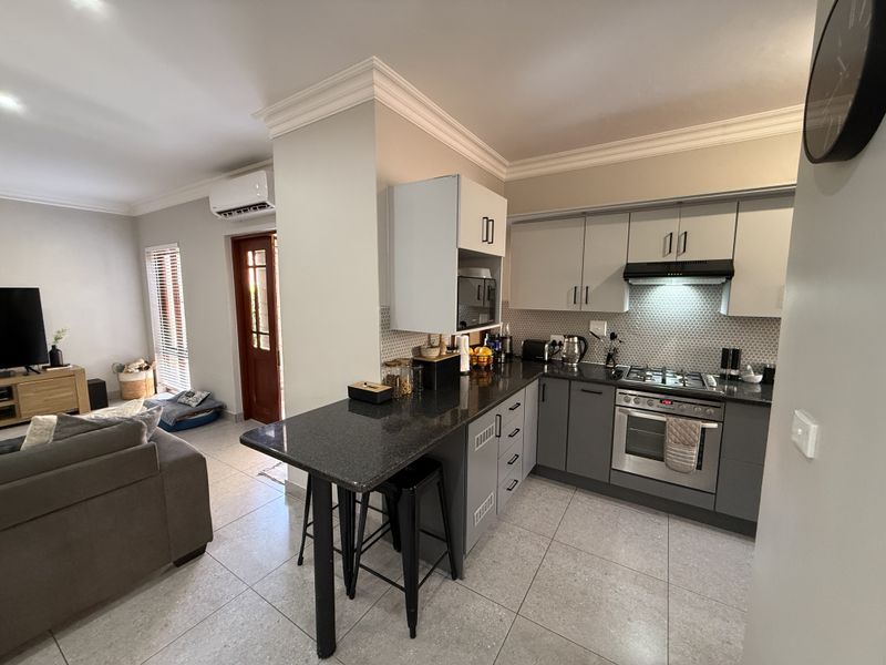 Modern open-plan kitchen featuring granite countertops, gas hob, built-in oven, and stylish mosaic backsplash, seamlessly flowing into the adjacent living area.