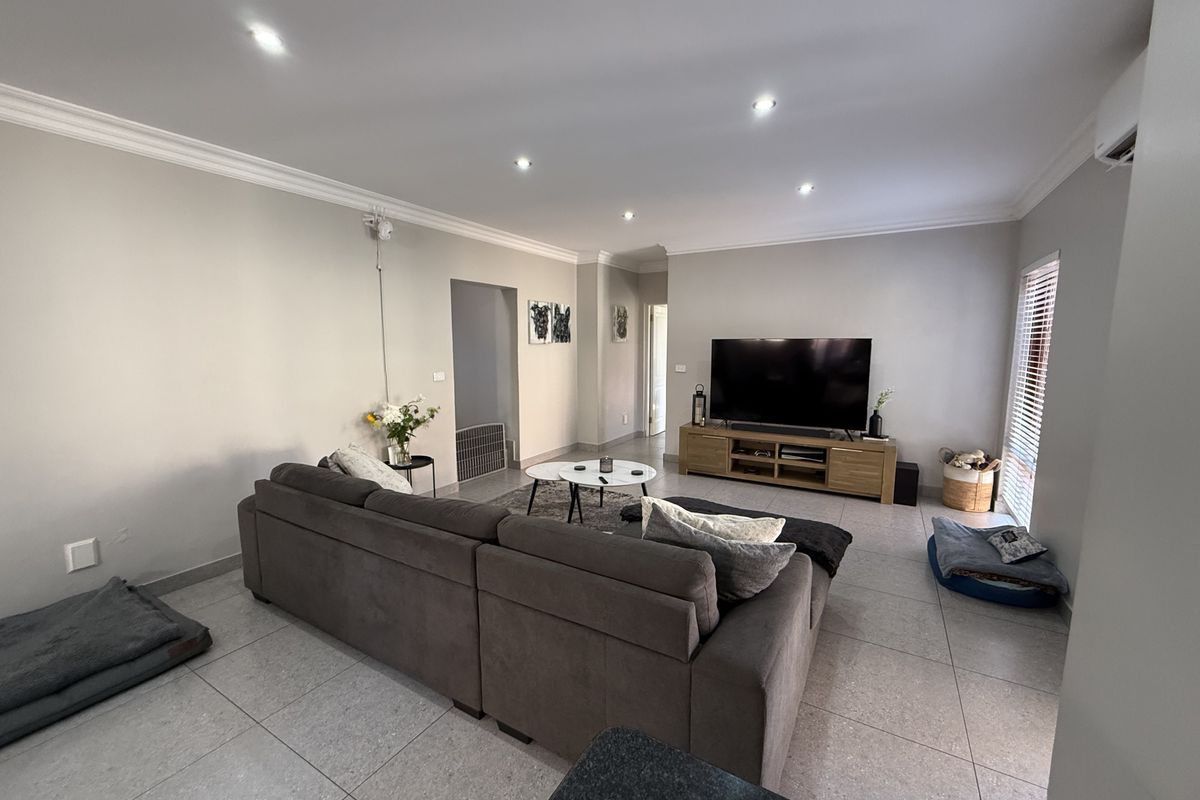 Spacious living room featuring neutral walls, tiled flooring, recessed downlighting, and a split system air conditioner for climate control.