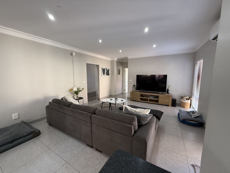 Spacious living room featuring neutral walls, tiled flooring, recessed downlighting, and a split system air conditioner for climate control.