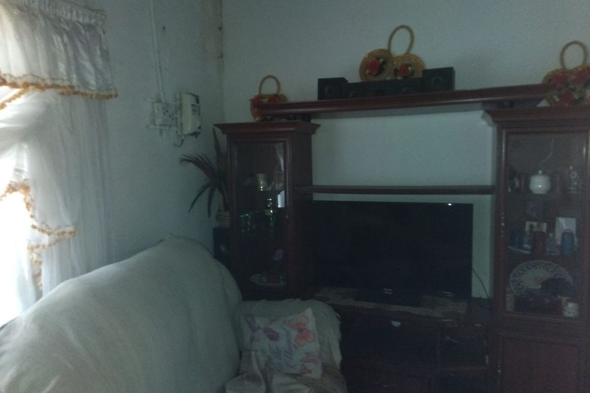A living room area featuring built-in display cabinetry, showing signs of wall staining and exposed electrical wiring.