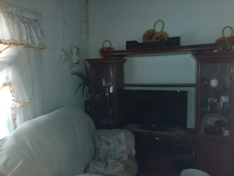A living room area featuring built-in display cabinetry, showing signs of wall staining and exposed electrical wiring.