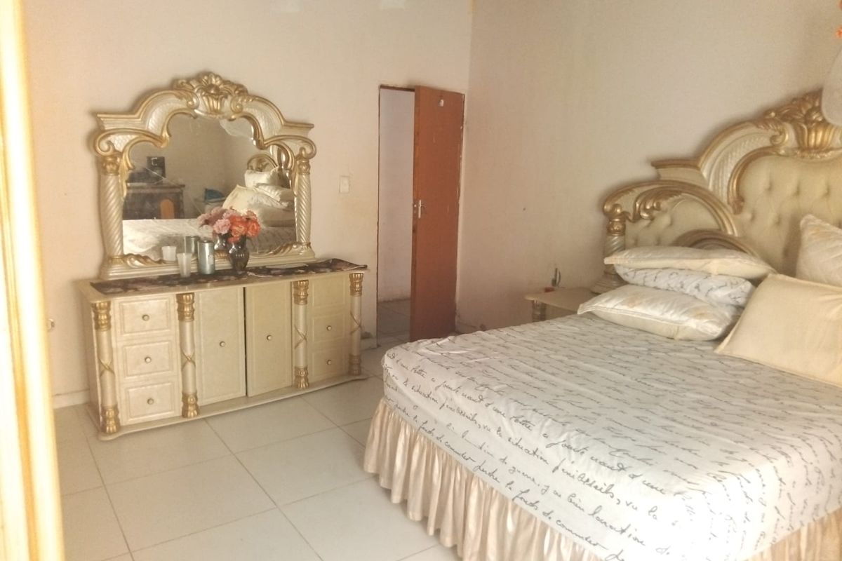 A bedroom featuring tiled flooring and an internal door, currently showing signs of unfinished ceiling work and wall maintenance requirements.