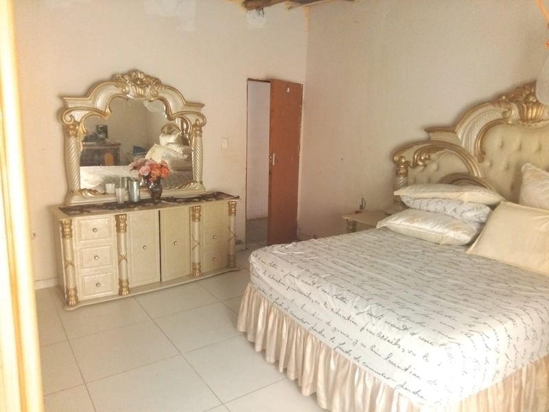 A bedroom featuring tiled flooring and an internal door, currently showing signs of unfinished ceiling work and wall maintenance requirements.