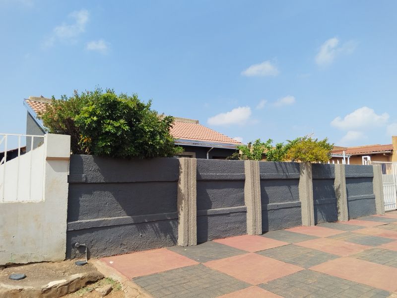 Front view of the property featuring a dark grey precast concrete boundary wall and a paved driveway area.