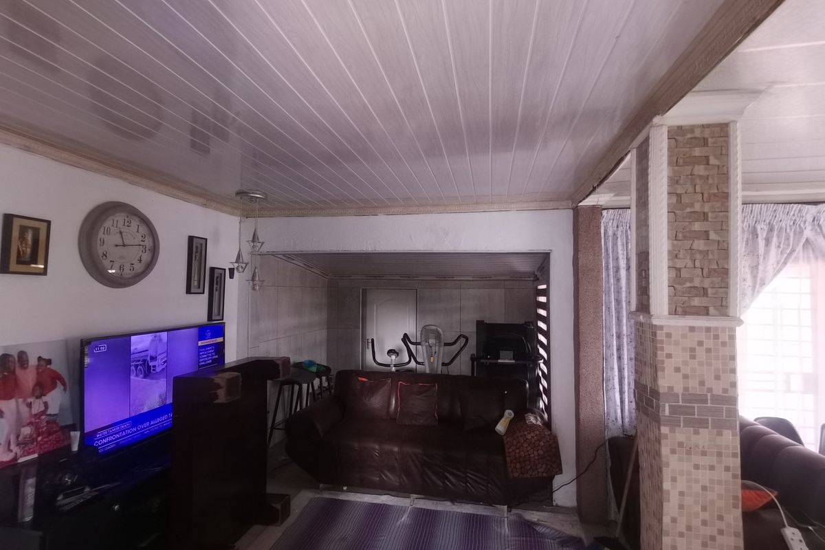 Living room area featuring a PVC panelled ceiling and a decorative tiled column, providing a functional space with potential for aesthetic updates.