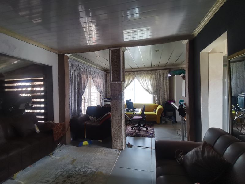 Open plan living area featuring tiled flooring, a central tiled support column, and recessed ceiling lighting.