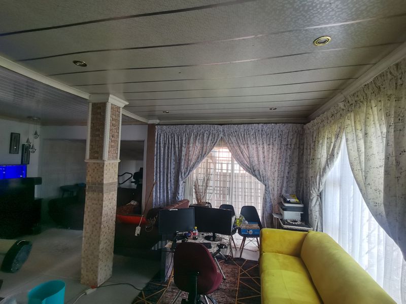 Open plan living area featuring a tiled structural column and panelled ceiling with recessed lighting, offering a versatile space for lounge and office use.