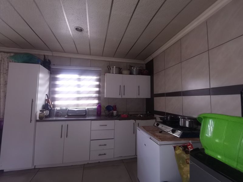 A functional kitchen featuring white cabinetry, tiled splashbacks, and a gas hob, offering a practical layout with potential for modern cosmetic updates.