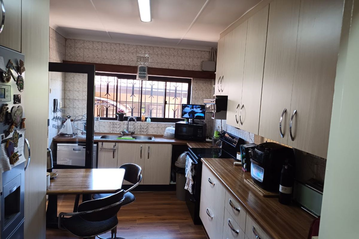 A functional kitchen featuring laminate cabinetry, wood-look countertops, tiled backsplash, and security bars on the window.