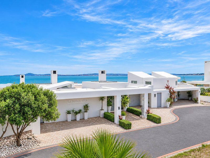 Modern coastal residence featuring a paved driveway, covered entrance, and clean architectural lines with expansive ocean views.