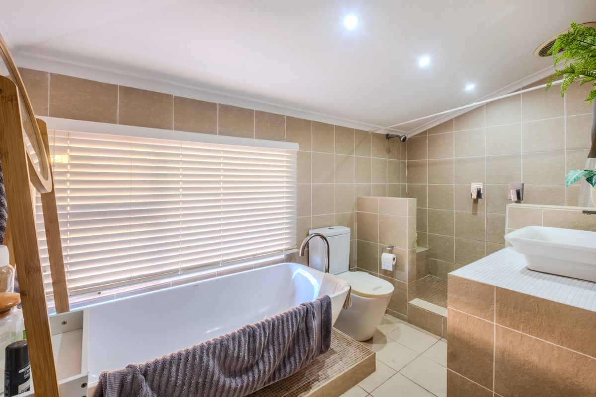 A functional bathroom featuring a freestanding bathtub, a walk-in shower, a vessel sink, and neutral wall tiling with recessed lighting.