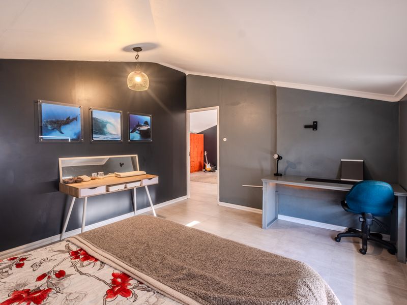 A bedroom featuring tiled flooring, a sloped ceiling, and dark accent walls, with an adjoining room visible through the doorway.