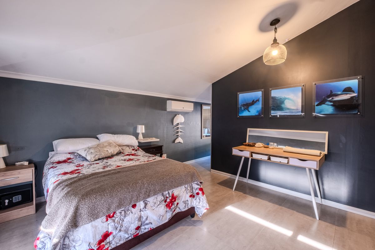 Spacious bedroom featuring tiled flooring, a split-system air conditioner, and modern dark accent walls, providing a comfortable and well-maintained living space.