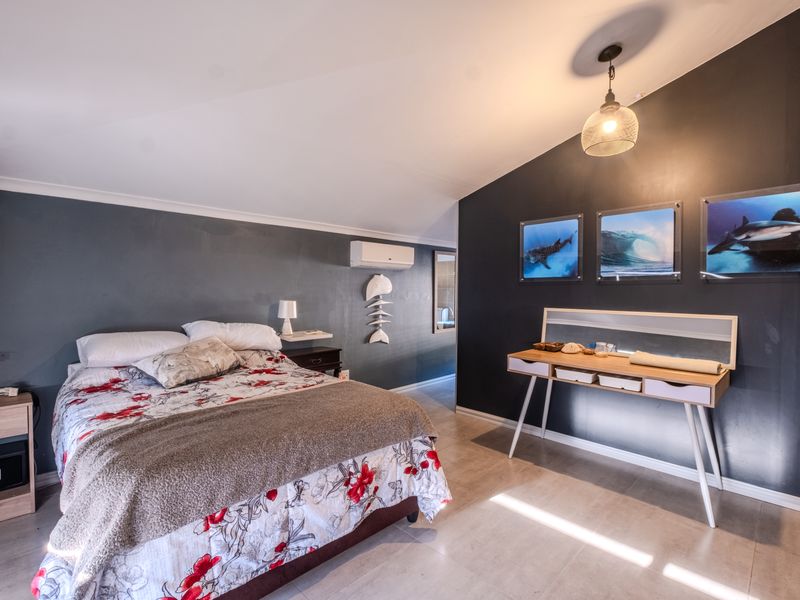 Spacious bedroom featuring tiled flooring, a split-system air conditioner, and modern dark accent walls, providing a comfortable and well-maintained living space.